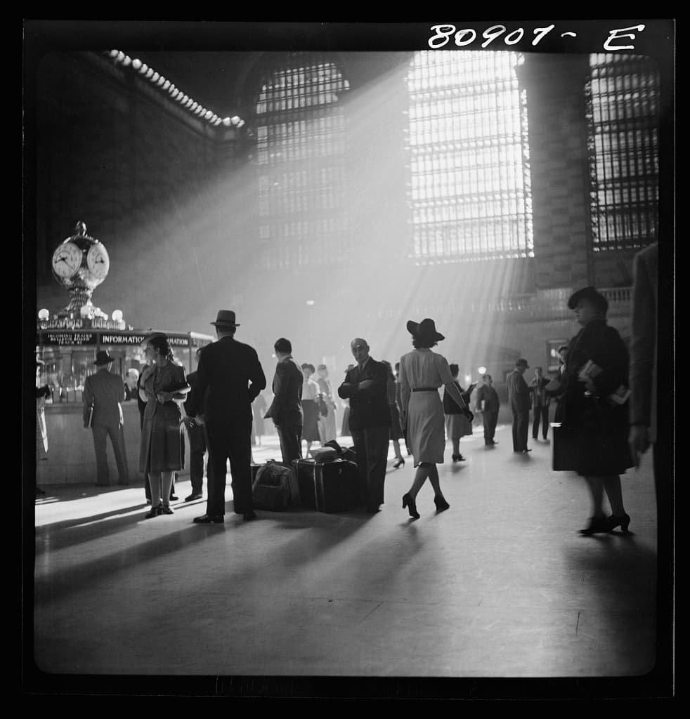 Travelers walking and waiting under shafts of sunlight at Grand Central Terminal in 1941.